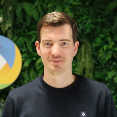 Portrait of Roel van Duijnhoven wearing a navy sweater in front of a green plant wall